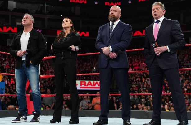 (From Left to Right) Shane McMahon, Stephanie McMahon, Paul 'Triple H' Levesque and Vince Mahon standing inside a WWE Monday Night RAW ring. The background shows the live audience and 'RAW' graphics dotted around the arena.   
