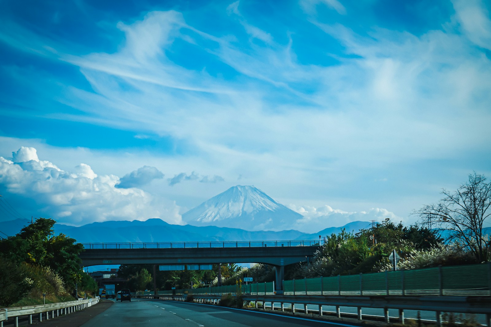 a highway with a bridge and a mountain in the background